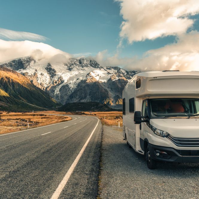 Una Autocaravana parada en el arcén de una carretera con un paisaje montañoso de fondo